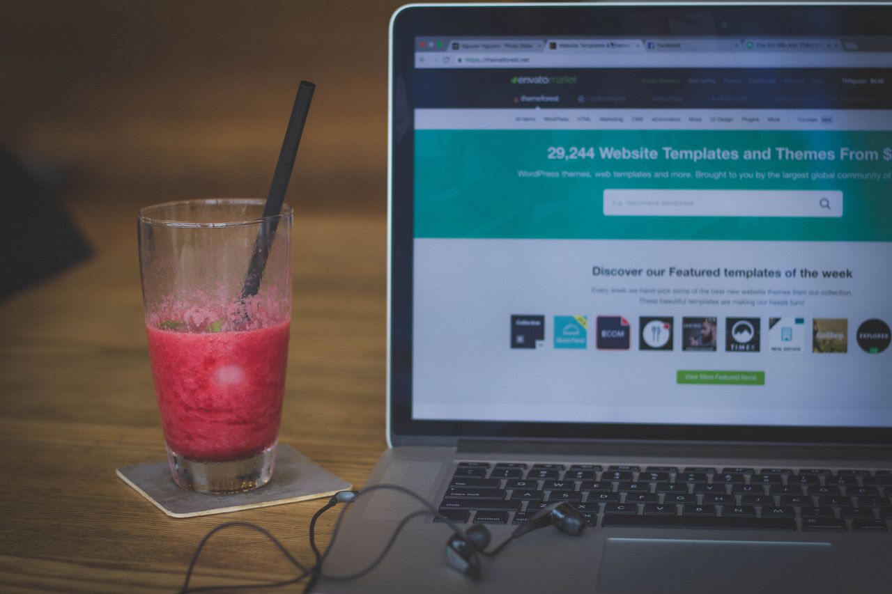 Mastering the First Impression: Your intriguing post title goes here A fruit shake on a desk next to a laptop displaying a website, blending work and refreshment.